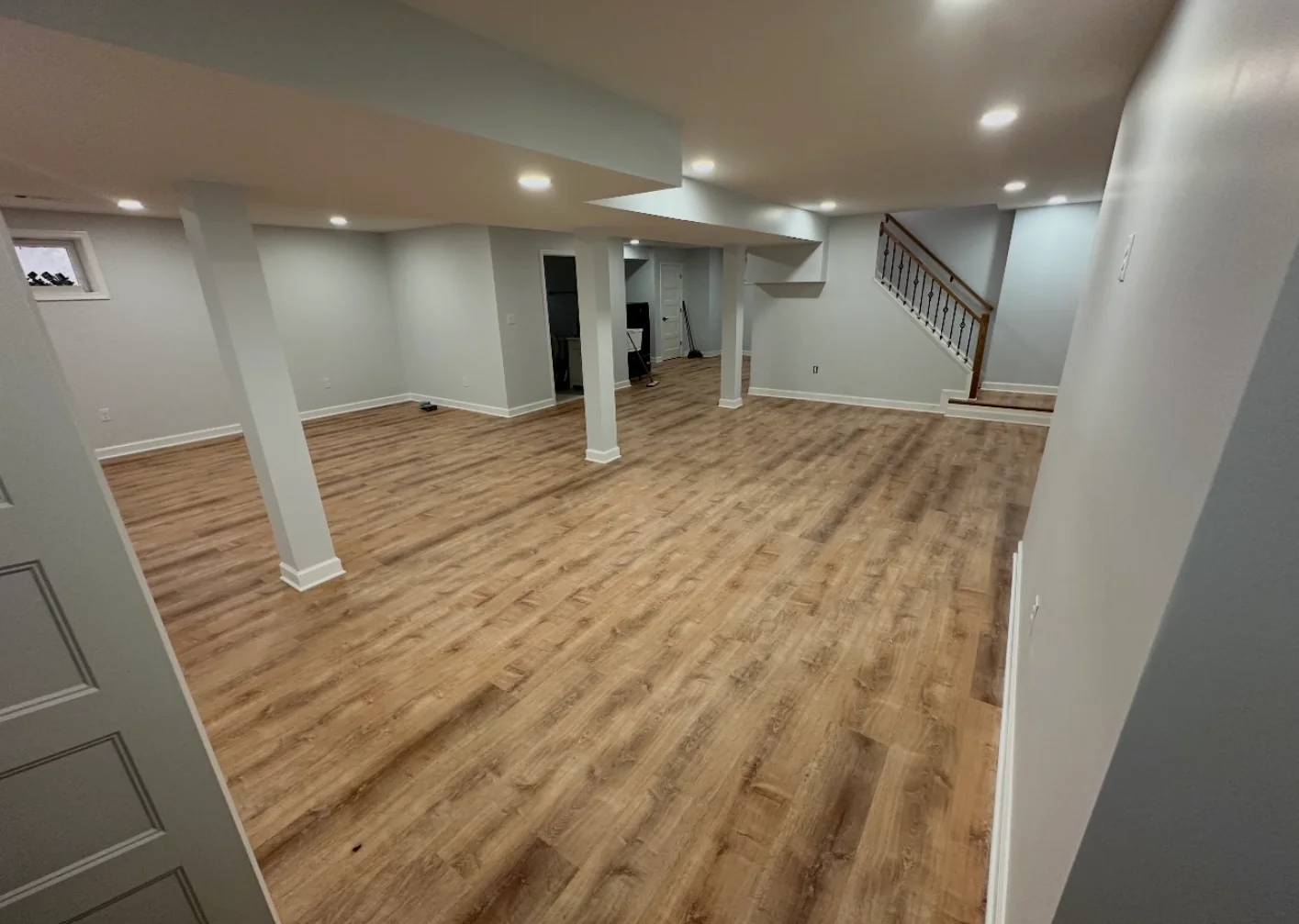 Large finished basement with columns, recessed lighting, and wood-look flooring