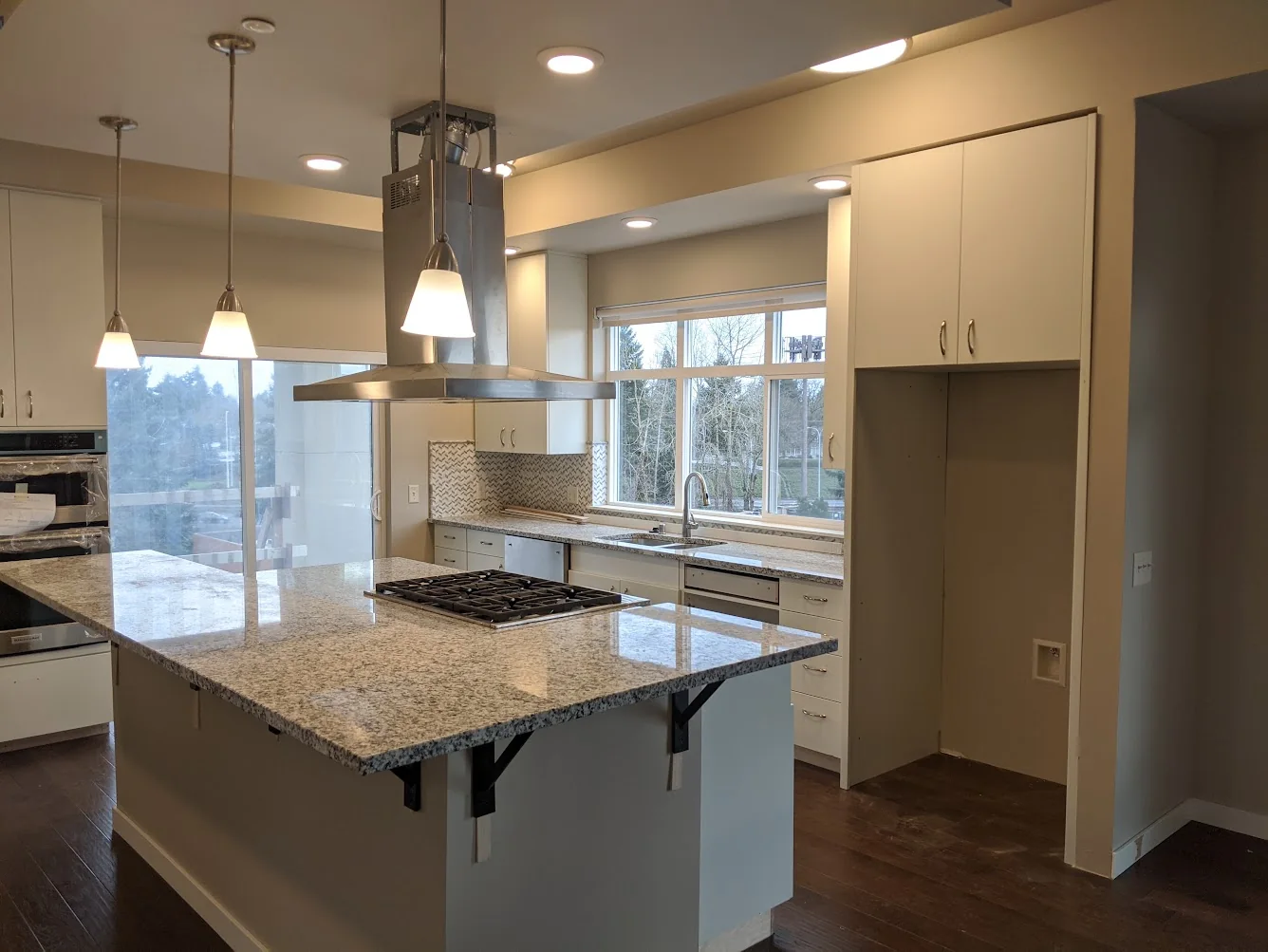 Finished kitchen with installed cabinetry, granite counters, island, and pendant lighting