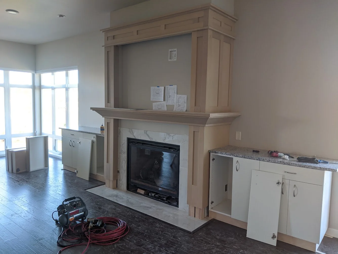 Detailed wood fireplace mantel and surrounding cabinetry during installation