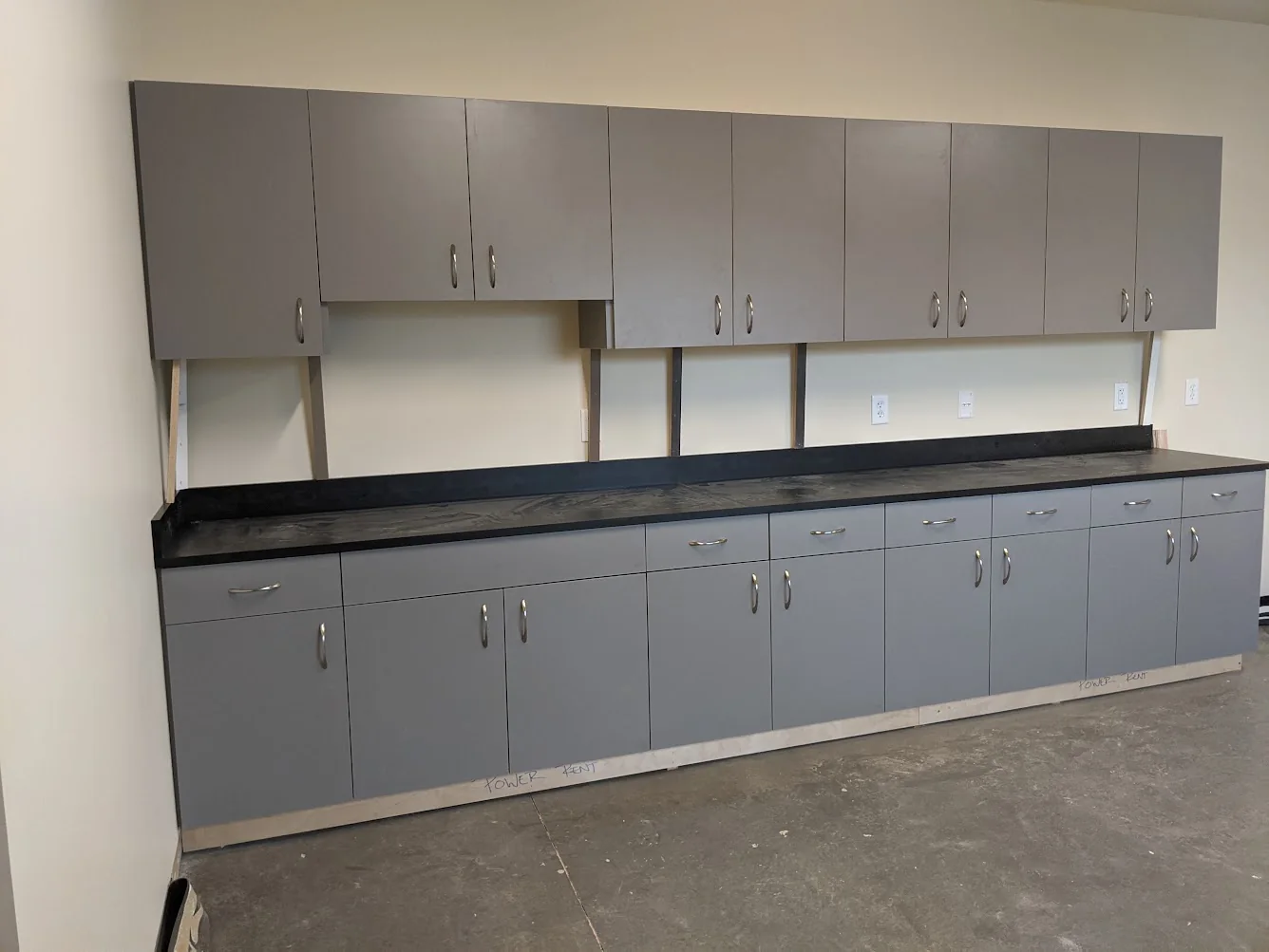 Long run of gray upper and lower cabinets with black countertop